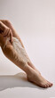 © master1305 - Female legs with feather touch test on smooth skin in soft studio background. Concept of dermatology sensitivity checks, laser epilation prep, skin care and modern aesthetic medicine.