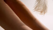 © master1305 - Close abstract view of smooth female legs with soft feather motion in warm background. Concept of aesthetic dermatology, laser prep visuals, cosmetic skin treatment and feminine care.