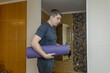 © Siniehina - Plus-size man practicing yoga at home on a mat, stretching to improve flexibility, joint mobility and posture. Concept of home fitness, rehabilitation, wellness and mindful movement.