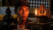 © MAS - Man in traditional attire gazes at a candle flame in a temple.