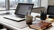 © ibhonk - Steaming speckled coffee mug resting beside an open silver laptop displaying a document, with a leather journal on a desk overlooking city buildings.