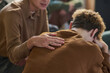© Mediaphotos - Teenager sitting with head in hands being comforted by young Asian man during group therapy session, supportive gesture showing empathy and emotional support