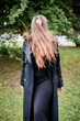 © TRAVELARIUM - Young woman with long hair covering face standing outdoors in black coat