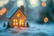 © Gatherina - Miniature house glowing warm light in winter snow