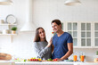 © BestForYou - Smiling man in a blue shirt is sitting at a kitchen table with a woman in a gray shirt. Happy expression.