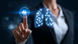 © zamuruev - Businesswoman touches virtual button to visualize lungs enhanced by AI technology. Dark background highlights focus on innovation in healthcare
