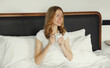 © rohappy - Happy smiling young woman enjoying with cup of hot coffee lying on bed at home