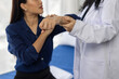 © Wasan - Female doctor examining the arm of a young female patient during a medical consultation in a hospital room, diagnosis and treatment for potential injury or pain.
