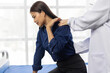 © Wasan - Senior doctor examining shoulder and back of young female patient sitting on bed in hospital room.