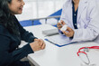 © Wasan - Asian female doctor holding medicine bottle and explaining prescription to senior patient while sitting and talking at desk in hospital room, healthcare and medical concept.