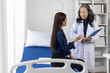 © Wasan - Doctor consulting with patient in medical office. The doctor holds a clipboard, while the patient listens attentivel.