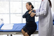 © Wasan - Doctor examining senior patient arm and shoulder in hospital room.