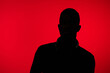 © SHOTPRIME STUDIO - Silhouette of a young Black man with headphones against a vibrant red background, conveying a sense of mystery and creativity in urban music culture
