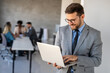 © NDABCREATIVITY - Young businessman using laptop computer in office. Manager thinks about successful financial ideas.