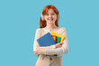 © Pixel-Shot - Teenage redhead girl with notebooks on blue background