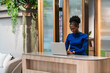 © artitwpd - An African woman in a blue top works on her laptop at a modern reception desk, surrounded by wooden and glass partitions, reflecting a professional, organized office environment.