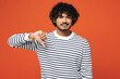 © ViDi Studio - Young sad unhappy disappointed dissatisfied Indian man he wear striped sweatshirt casual clothes showing thumb down dislike gesture isolated on plain red orange background studio. Lifestyle concept.