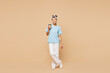 © ViDi Studio - Full body young woman of African American ethnicity wears blue t-shirt casual clothes hold takeaway delivery craft paper brown cup coffee to go isolated on plain beige background. Lifestyle concept.