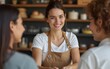 © Sebastian - A candid shot of a smiling female baker, who's also the shop owner, offering exemplary customer service as she hands a customer their order in her retail store. High quality