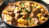 Hearty stew featuring tender meat chunks, soft potatoes and green herbs in a creamy brown gravy, steaming hot