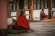 © Travel 'n' Lifestyle - Walakha, Bhutan - 19 September 2025: View of monks in vibrant red robes sitting in quiet contemplation near Sangchhen Dorji Lhuendrup Lhakhang Nunnery.