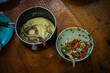 © Travel 'n' Lifestyle - Ha, Bhutan - 26 September 2025: View of two bowls, one filled with a creamy, pale green stew and the other a vibrant mix of chopped red tomatoes, green herbs and dark sauce, resting on a wooden table.