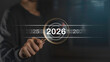 © The KonG - Future focus and annual goal. Hand holding magnifying glass highlighting year 2026 with a target, representing planning, vision, resolution, and business strategy for the new year.
