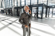 © Jelena - Confident Businessman Talking on Phone in Modern Airport Lobby