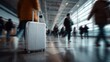 © Amal - A silver suitcase stands in a busy airport, with blurred figures walking past