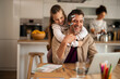 © Jelena - Father Working from Home While Daughter Playfully Interrupts in the Kitchen