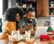 © Lumos sp - Happy young afro american couple having fun preparing food and looking for recipes online using a laptop in kitchen