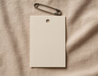 © Andika - Beige rectangular clothing price tag mockup with safety pin on fabric background
