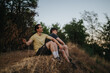 © qunica.com - Two men sit on a dry hillside after a rugged hike, taking a moment to relax and chat. The scene conveys friendship, outdoor fitness, and the calm energy of nature.