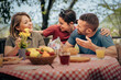 © Lomb - Friends enjoying a warm outdoor meal together during a joyful spring gathering.