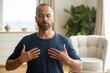 © Macrostock - Bearded middle aged man meditating at home finding inner peace and balance