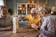 © Migma_Agency - Seniors friends playing jenga board game at home