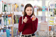 © JackF - Young European woman holds bottles of nail polish in her hands and chooses a beautiful color. Shopper looking at nail care products in store