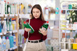 © JackF - Brunette woman carefully choosing detergents in supermarket. Buyer makes a purchase of household chemicals for the house