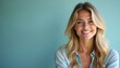 © Viktor - Attractive young blonde woman with blue eyes smiles warmly at camera, indoor studio portrait. Wears casual denim shirt, long wavy hair frames face, soft light features. Confident, serene expression.