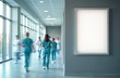© Viktor - Medical staff walk in hospital corridor past empty poster frame near large window. Busy healthcare workers move along bright hallway, blurred figures busy with work.