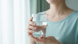 © miko - 透明なグラスに入った水を持つ女性の健康的な水分補給のライフスタイルイメージ