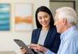 © Meow Creations - Smiling female financial advisor helping senior man review documents on a digital tablet during a consultation.