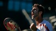 © Tiwakeat - Intense male tennis player shouts celebrating victory while gripping racket on court
