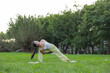 © leungchopan - Active woman performing yoga on green grass at park