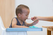 © leungchopan - Mother feeding baby with spoon at home
