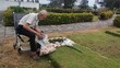 © Creativa Images - A lonely, elderly man in a wheelchair, mourning a loved one, tenderly places flowers on a grave or memorial in a peaceful cemetery park. Symbolizes loss, remembrance, grief, old age, and enduring love