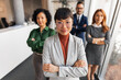 © Jelena - Confident Professionals Standing In an Office Environment Displaying Teamwork and Leadership