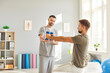 © Studio Romantic - Young man doing sport exercise using dumbbells with support from male friendly nurse in clinic. Physiotherapist helping patient in lifting dumbbell. Physiotherapy and physical rehabilitation concept.