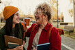 © La Famiglia - Female students laughing, enjoying coffee on campus