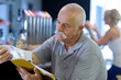 © auremar - elderly man reading magazine in a bistro
